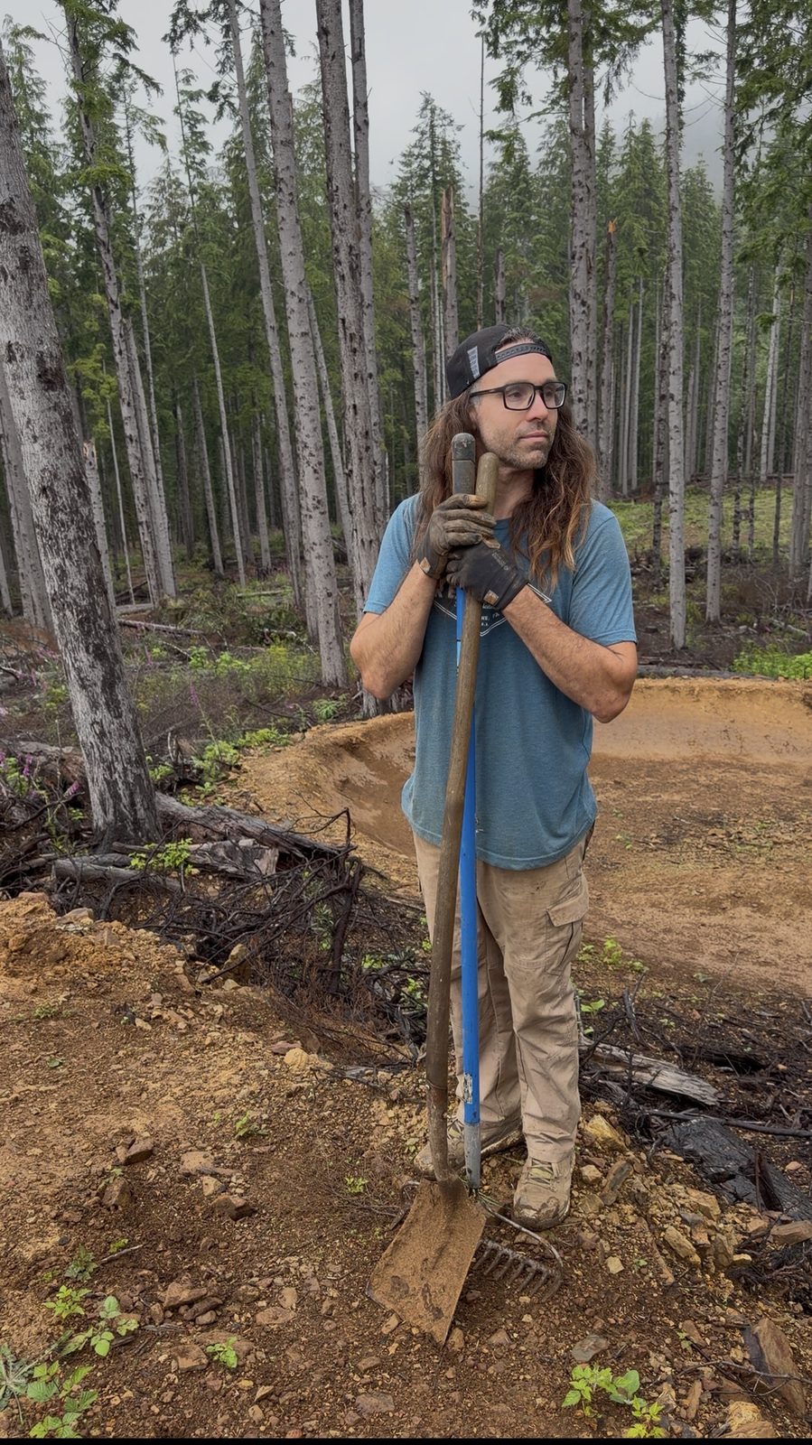 Ryan Rodriguez with hand tools beside a newly shaped berm at Buzzard Butte, 2026